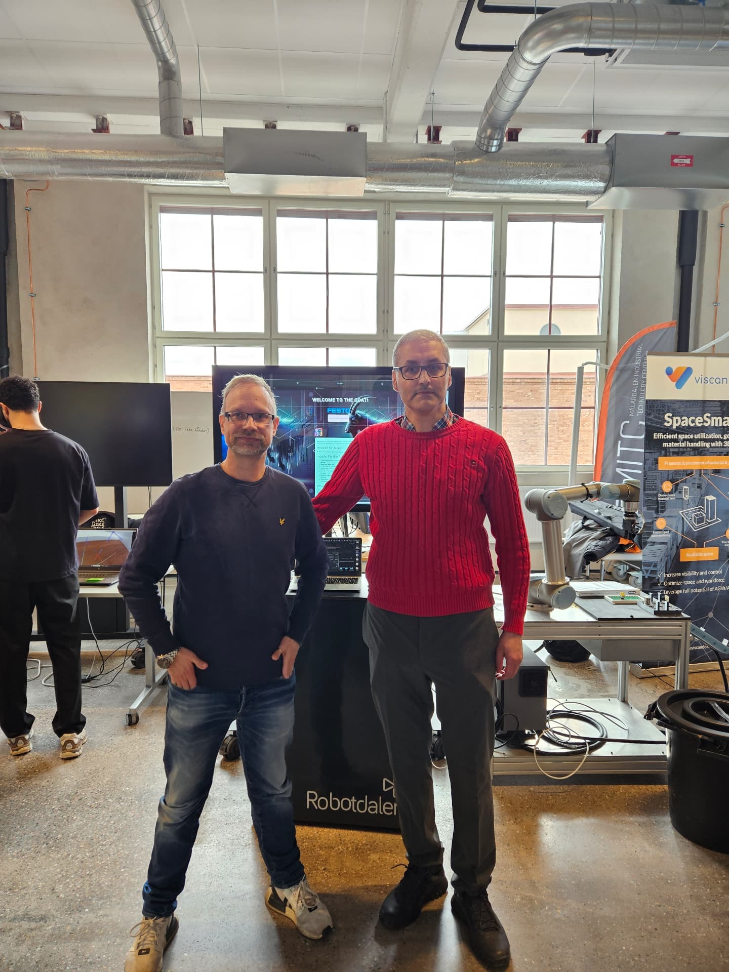 Two people standing in front of the testbed screen during the demonstration